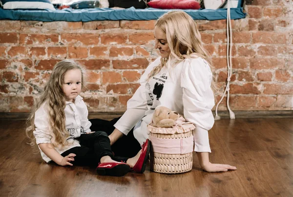 Pretty blonde mother and her caucasian little daughter sitting on the floor with big box gift and happy together — Stock Photo, Image