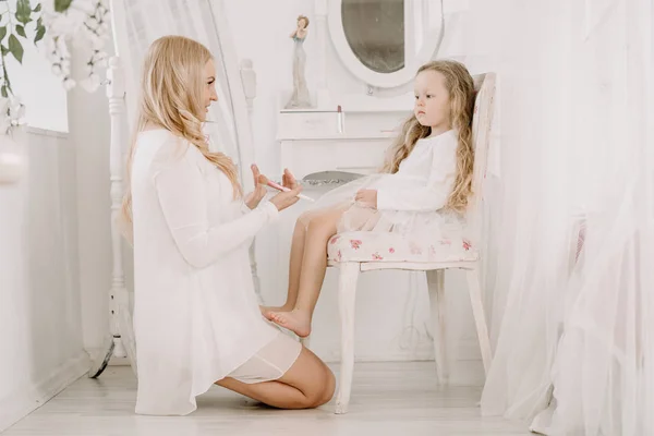 Beautiful woman and child girl doing make up each other on white room background