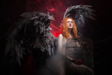 an evil tempting woman with large demon wings holds an Apple in a large cage and beckons to sin. Halloween photo plus size girl with red hair on a huge Gothic throne. clipart