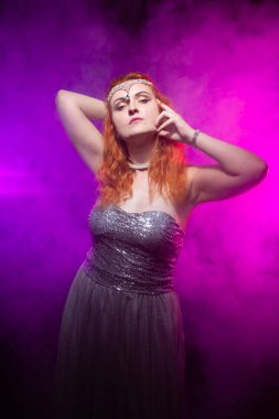 Olgun artı boyutu gri gece elbisesi içinde kırmızı saçlı kadın cadılar bayramı için hazır koyu duman arka plan üzerinde poz.