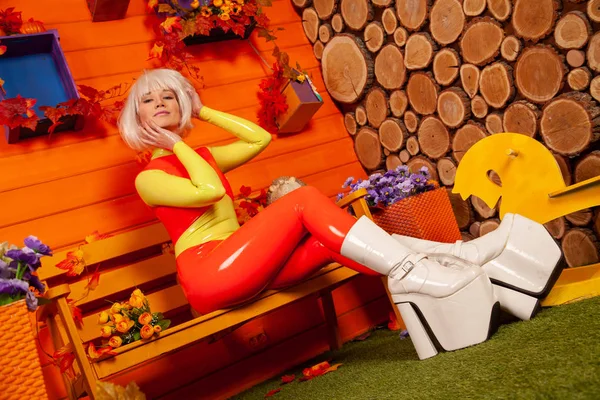 Hete mooie blonde vrouw in heldere kleurrijke latex rubber Catsuit klaar voor Halloween herfst feest en poseren in de buurt van haar oranje huis — Stockfoto