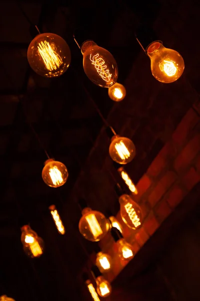 Klassiska olika retro glödlampor hängande på tegelvägg bakgrund på natten — Stockfoto