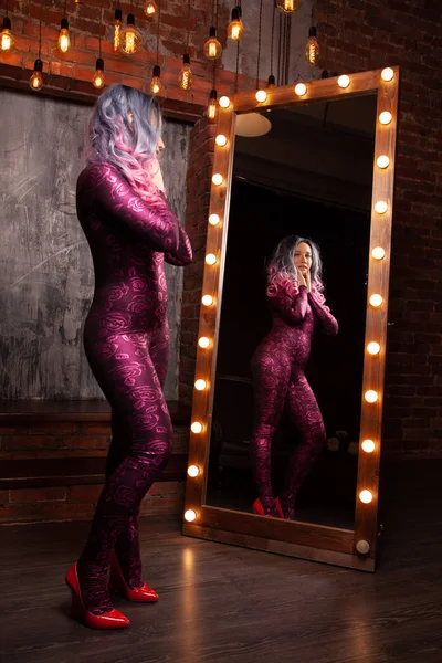 Hübsche junge schlanke Frau steht in der Nähe eines riesigen Spiegels mit Glühbirnen — Stockfoto