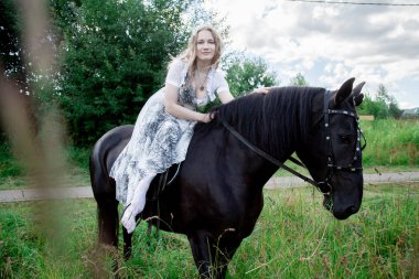 Güzel beyaz kız bir atla yürüyor ve yaz tatilini kırsalda geçiriyor..