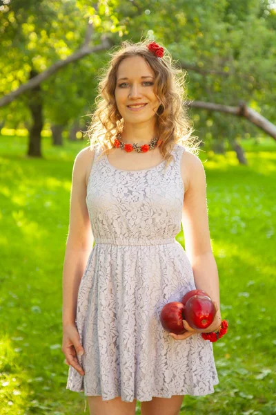 Jovem mulher em branco bonito polka dot vestido andando em um jardim de maçã em um lindo dia ensolarado de verão — Fotografia de Stock