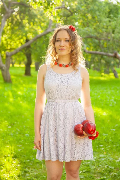 Mujer joven en blanco lindo vestido de lunares caminando en un jardín de manzanas en un hermoso día soleado de verano — Foto de Stock