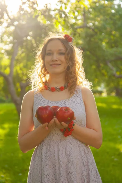 Junge Frau in weißem, niedlichem Tupfen-Kleid, die an einem schönen, sonnigen Sommertag in einem Apfelgarten spaziert — Stockfoto