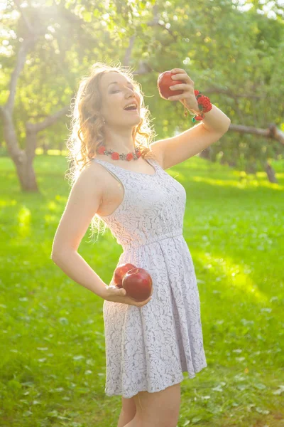 若いです女性で白いかわいいですポルカドットドレス歩くとアップルガーデンで美しい日当たりの良い夏の日 — ストック写真