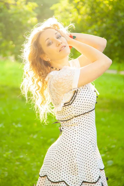 Ung kvinna i vit söt prick klänning promenader i en äppelträdgård på en härlig solig sommardag — Stockfoto
