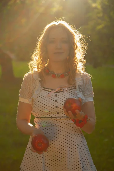 Jovem mulher em branco bonito polka dot vestido andando em um jardim de maçã em um lindo dia ensolarado de verão — Fotografia de Stock