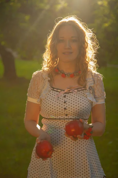 Jovem mulher em branco bonito polka dot vestido andando em um jardim de maçã em um lindo dia ensolarado de verão — Fotografia de Stock