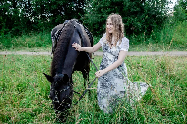 Retrato de camisa xadrez de menina com cavalo preto na fazenda de cavalos.