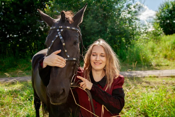 美しい白人の若い女の子は馬と一緒に歩いて、田舎で夏を楽しんでいます. — ストック写真