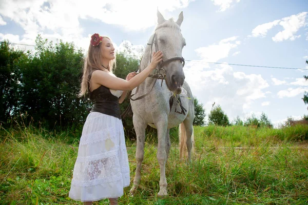 Krásná kavkazská mladá dívka kráčí s koněm a má léto na venkově. — Stock fotografie