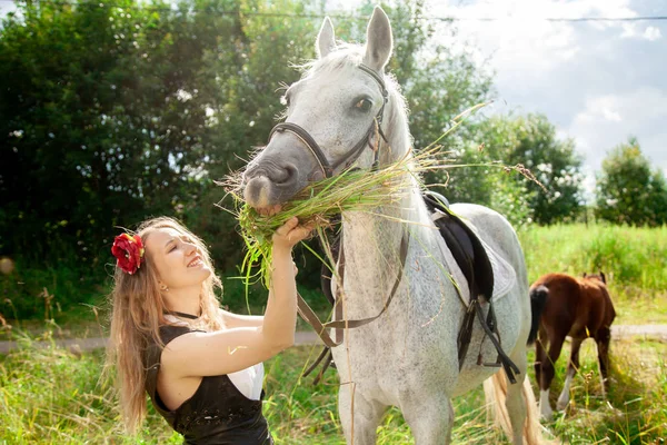 Mooi Kaukasisch jong meisje wandelen met een paard en geniet van de zomer op het platteland. — Stockfoto