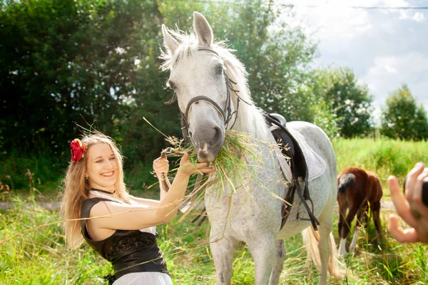 Gyönyörű kaukázusi fiatal lány séta egy ló, és élvezi a nyári vidéken. — Stock Fotó