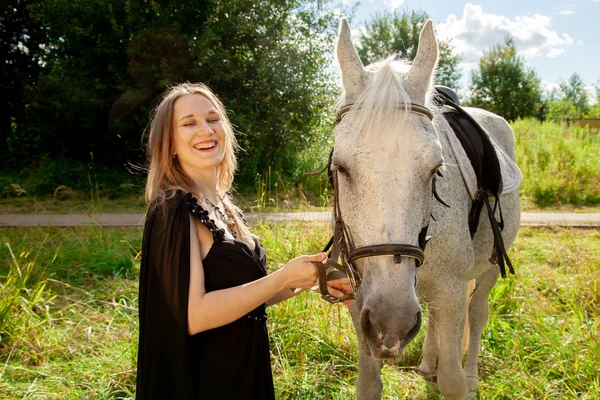 Belle jeune fille caucasienne marchant avec un cheval et profite de l'été dans la campagne . — Photo