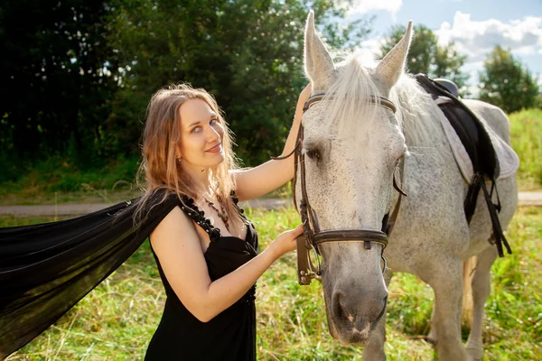 Schöne kaukasische junge Mädchen zu Fuß mit einem Pferd und genießt die Sommerzeit in der Natur. — Stockfoto