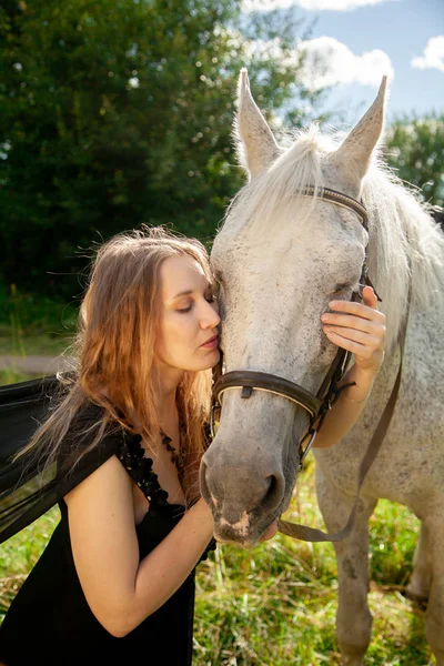 Belle jeune fille caucasienne marchant avec un cheval et profite de l'été dans la campagne . — Photo