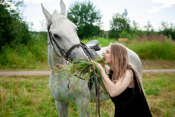 Красива біла молода дівчина гуляє з конем і насолоджується літнім часом у сільській місцевості . — стокове фото