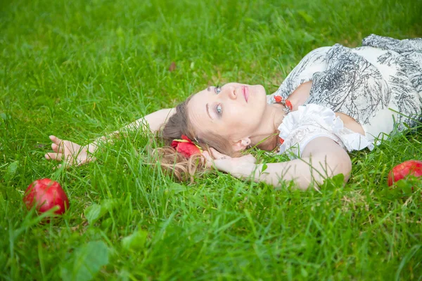 Beyaz yaz elbisesi ve dantel çoraplı genç, şık bir kız akşamları çimlerin üzerinde oturuyor. — Stok fotoğraf