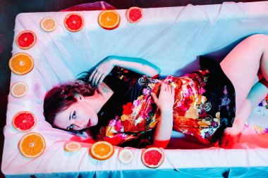 Spa banyosunda portakal dilimleriyle rahatlayan genç bir kadın. Sağlık kavramı.