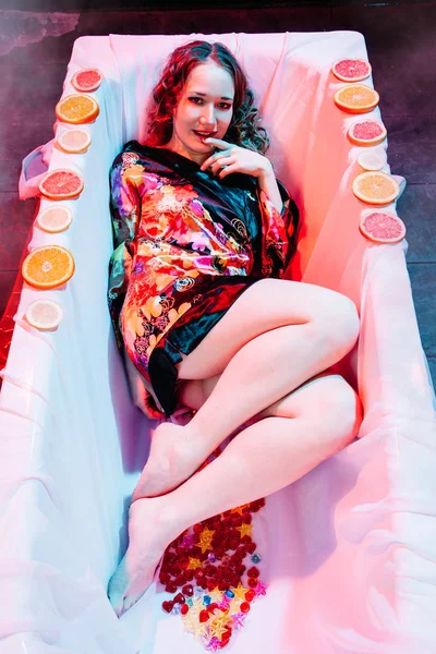 Junge Frau entspannt sich im Wellnessbad mit Orangenscheiben. Welness-Konzept. — Stockfoto