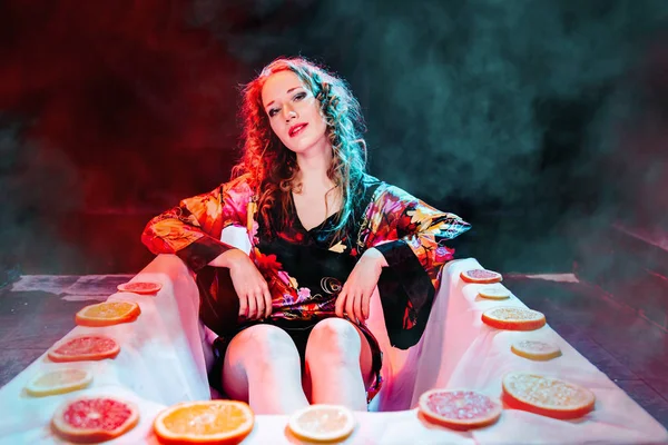 Junge Frau entspannt sich im Wellnessbad mit Orangenscheiben. Welness-Konzept. — Stockfoto