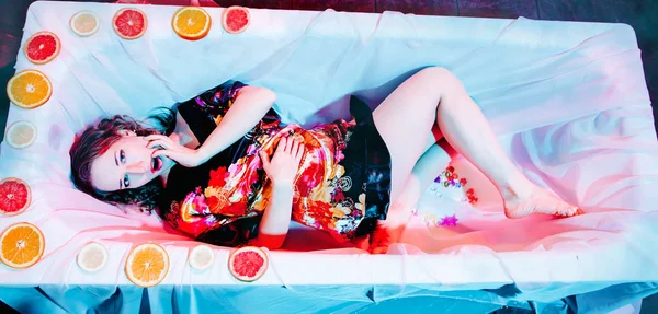Νεαρή γυναίκα χαλαρώνει στο μπάνιο του Spa με φέτες πορτοκαλιού. Έννοια συγκολλητικότητας. — Φωτογραφία Αρχείου