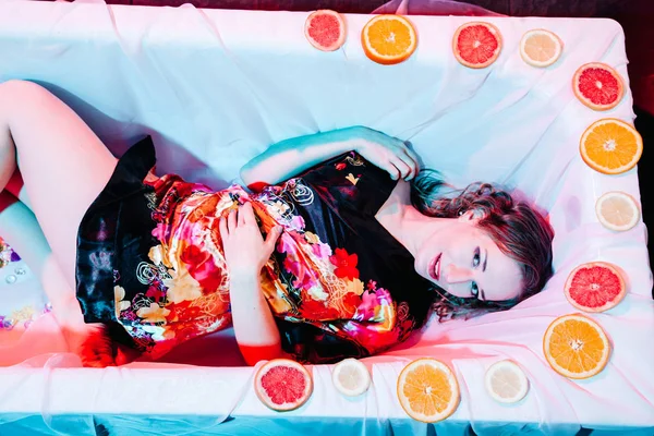 Mujer joven relajándose en la bañera de hidromasaje con rodajas de naranjas. Concepto de solidez . —  Fotos de Stock