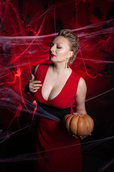 Mulher à noite vestido clássico posando com abóbora em fundo preto Halloween com teia de aranha — Fotografia de Stock