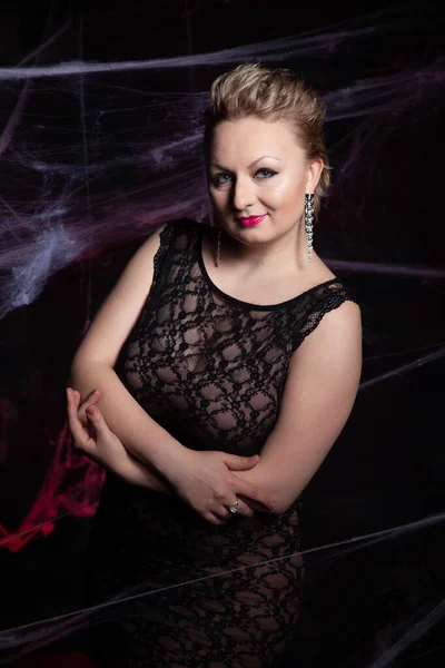 Женщина в вечернем классическом платье позирует на черном фоне Хэллоуина с паутиной — стоковое фото