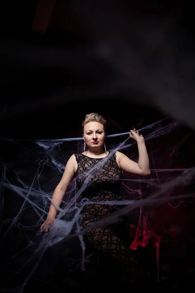 Woman in evening classic dress posing on black Halloween background with spider web — Stock Photo, Image