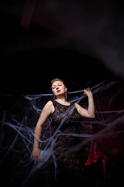 Woman in evening classic dress posing on black Halloween background with spider web — Stock Photo, Image