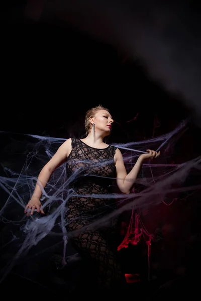 Woman in evening classic dress posing on black Halloween background with spider web — Stock Photo, Image