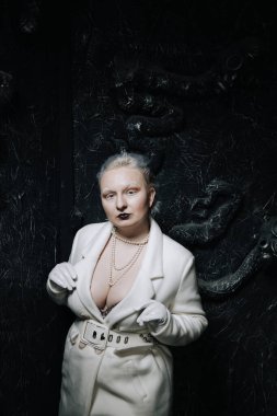 Stüdyoda siyah arka planda beyaz elbiseli sıradışı bir kızın portresi. Kadın artı boyut albino. Her insanda güzellik kavramı