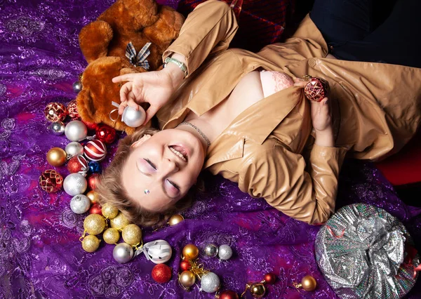 아름다운 크리스마스 장난감 공 과 포장된 선물로 둘러싸인 바닥에 누워 있는 한 젊은 여성의 맨 위 사진 — 스톡 사진