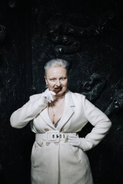 Genç ucube artı boyut albino kadın açgözlülükle yiyor ve siyah arka planda çikolatayı seviyor. kıvrımlı kısa saçlı beyaz elbiseli kız..