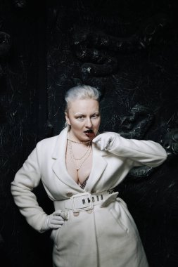 Genç ucube artı boyut albino kadın açgözlülükle yiyor ve siyah arka planda çikolatayı seviyor. kıvrımlı kısa saçlı beyaz elbiseli kız..