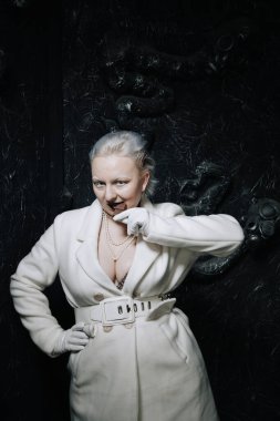 Genç ucube artı boyut albino kadın açgözlülükle yiyor ve siyah arka planda çikolatayı seviyor. kıvrımlı kısa saçlı beyaz elbiseli kız..