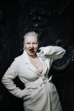 Genç ucube artı boyut albino kadın açgözlülükle yiyor ve siyah arka planda çikolatayı seviyor. kıvrımlı kısa saçlı beyaz elbiseli kız..