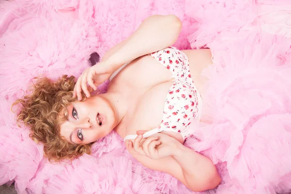 Ovanifrån på en ung lockig kvinna med plus storlek kropp liggande i rosa tyg — Stockfoto