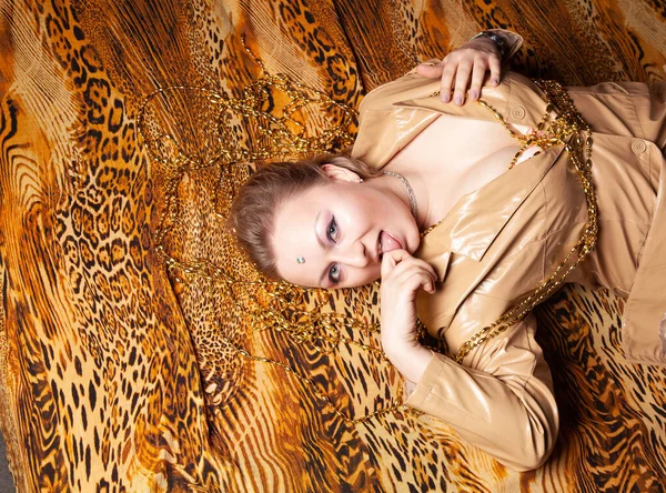 Draufsicht auf charmantes Plus-Size-Mädchen mit kurzen Haaren liegt in lederbeiger Jacke auf einem Blatt mit Leopardenmuster — Stockfoto