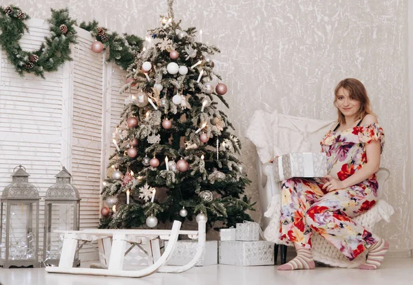 Mulher feliz grávida celebra o Natal no quarto decorado com abeto de ano novo — Fotografia de Stock