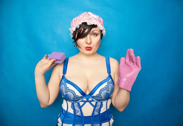 Прелестный счастливый плюс размер короткие волосы женщина в синем белом белье с резиновой перчаткой и губкой для мытья посуды на твердом фоне в студии — стоковое фото