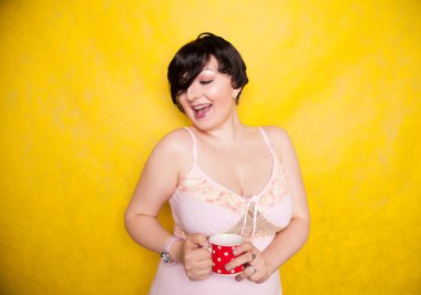 Ayrıca elinde kırmızı benekli seramik kahve ya da parlak sarı arka planda çay fincanı tutan pembe elbiseli bir kadın.