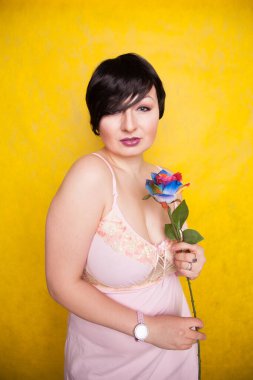 Sarı arka planda suni çiçekli güzel bir kadın.