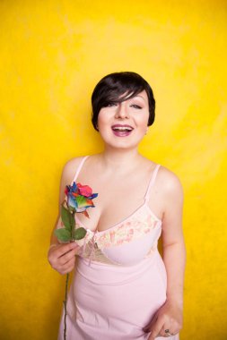 Sarı arka planda suni çiçekli güzel bir kadın.