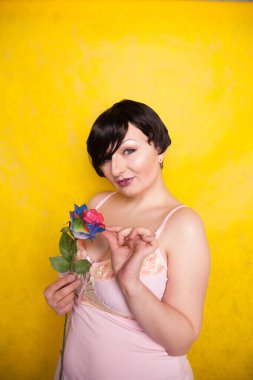 Sarı arka planda suni çiçekli güzel bir kadın.