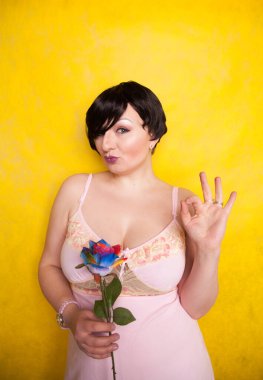 Sarı arka planda suni çiçekli güzel bir kadın.